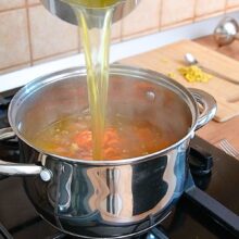 Se toarnă supa fierbinte de legume peste morcovii copți pentru supă cremă cu măr și ghimbir