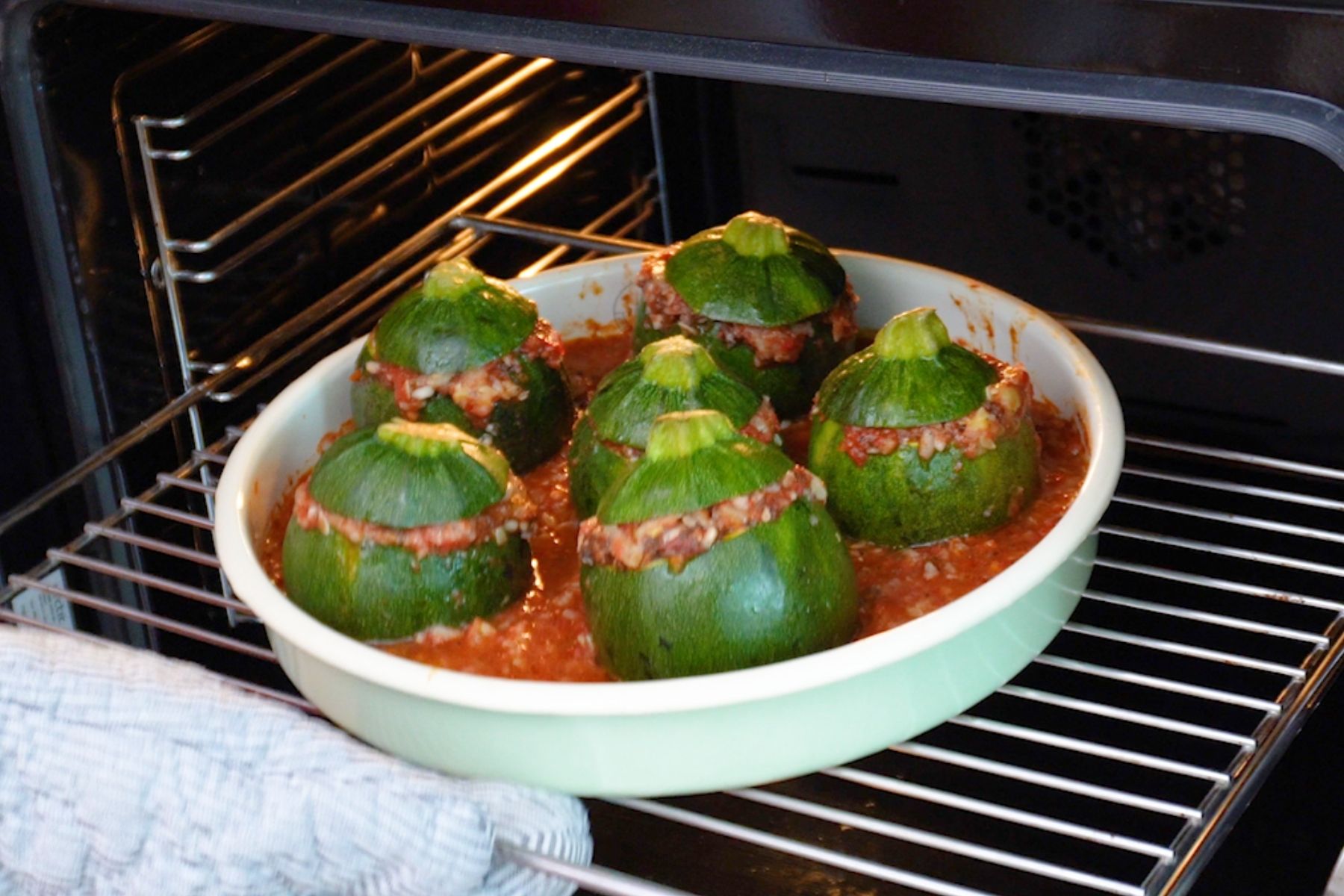 Dovlecei umpluți cu orez și ciuperci, în tavă cu sos de roșii, introduși în cuptor pentru coacere