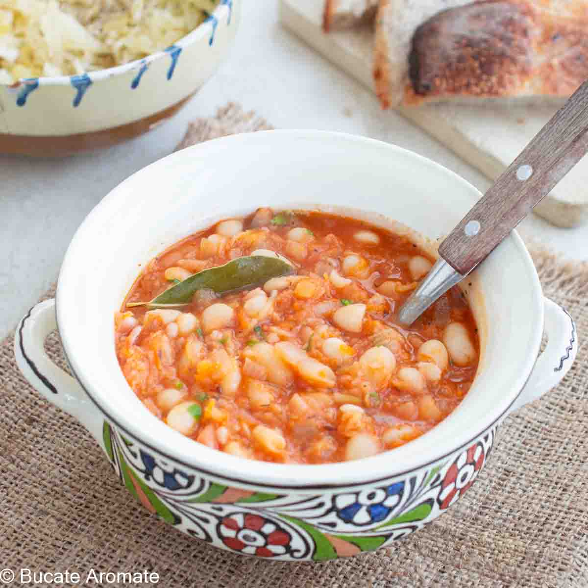 Iahnie de fasole boabe, cremoasă și aromată, într-un bol tradițional, decorată cu frunză de dafin