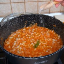 Mâncare de fasole cu sos de roșii, legume și condimente, la care se adaugă sare pentru gust final