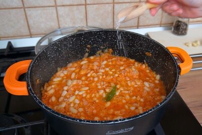Mâncare de fasole cu sos de roșii, legume și condimente, la care se adaugă sare pentru gust final