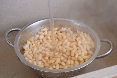 Fasole albă fiartă, clătită sub apă curentă pentru a elimina spuma și substanțele iritante