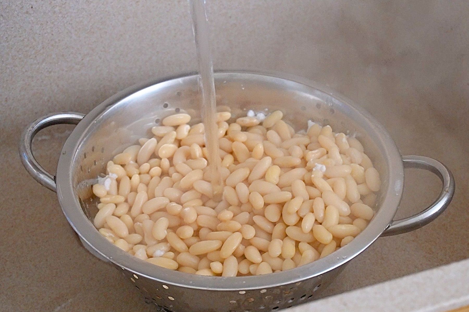 Fasole albă fiartă, clătită sub apă curentă pentru a elimina spuma și substanțele iritante