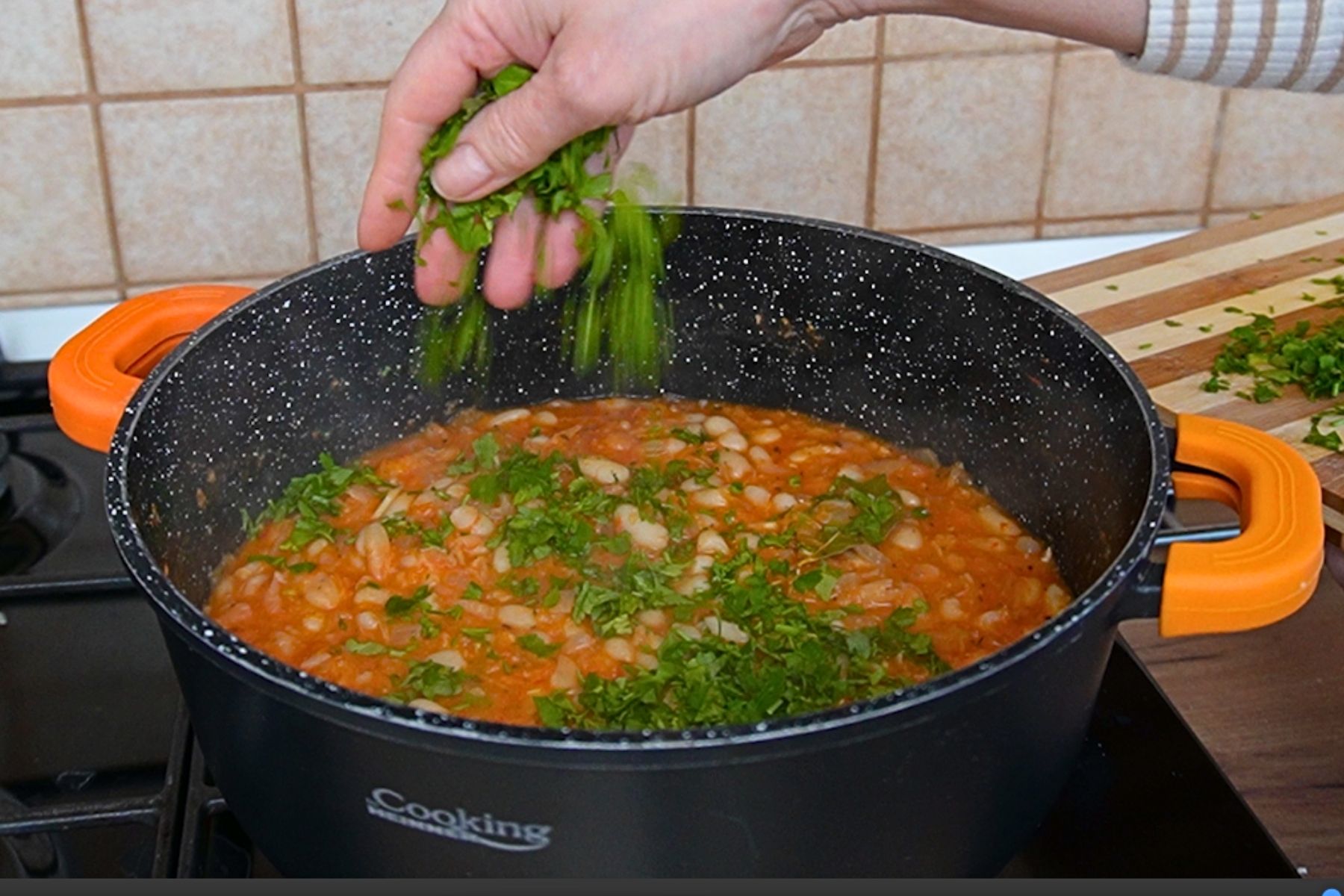 Mâncare de fasole cu sos tomat și legume, presărată cu pătrunjel proaspăt pentru un plus de aromă