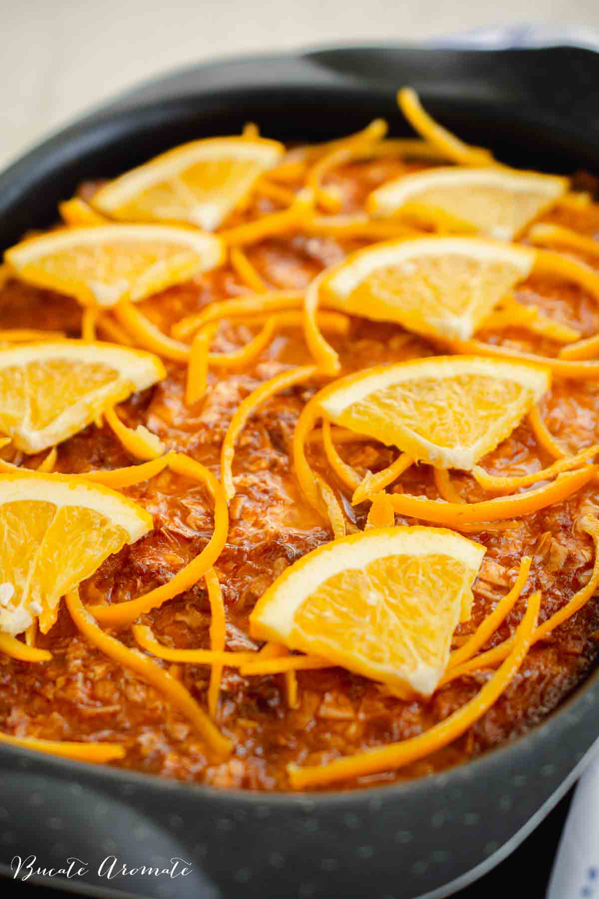 Portokalopita decorată cu felii de portocale și coajă rasă, prăjitură grecească însiropată cu foi de plăcintă