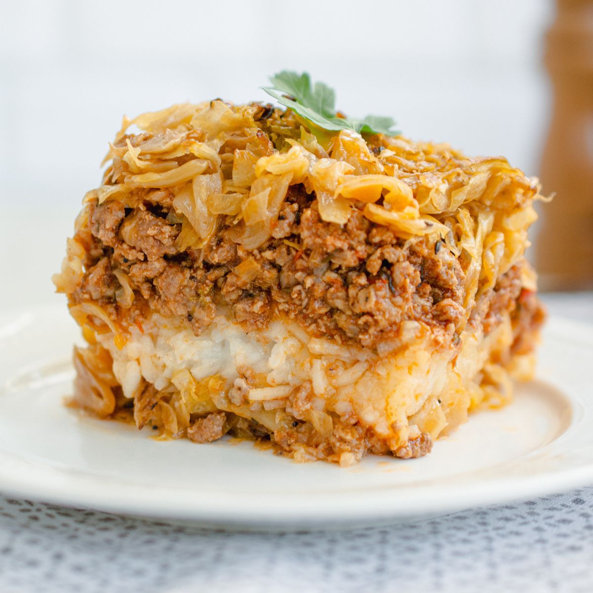 Rețetă de varză a la Cluj servită pe farfurie, cu smântână și tacâmuri, preparat tradițional românesc gătit la cuptor