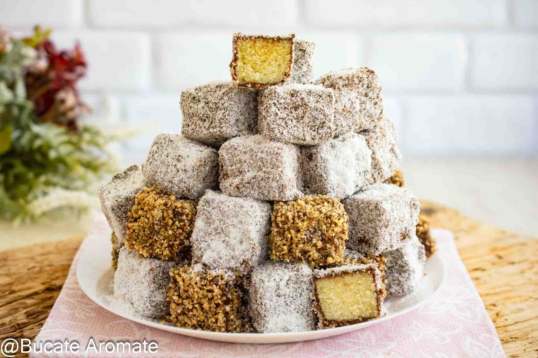 Platou cu lamington vegan, cuburi cu blat pufos de post, glazură de ciocolată și înveliș de cocos sau nucă mărunțită.