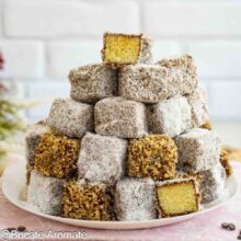Cuburi de prăjitură tăvălită de post cu cocos și nucă, alături de o bucată tăiată care arată blatul aromat cu lămâie și vanilie.