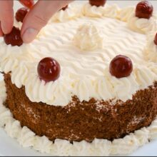 Decorarea tortului cu cremă de mascarpone și vișine pe margine.