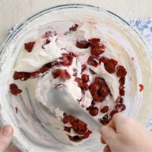 Adăugarea vișinelor scurse în crema de mascarpone pentru umplutura tortului.