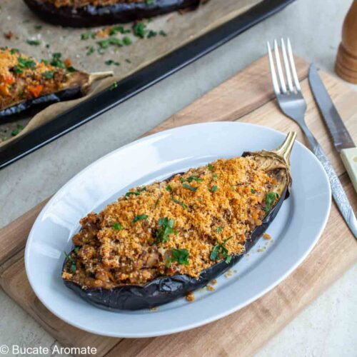 Vânătă umplută cu quinoa și linte servită pe o farfurie albă, decorată cu pătrunjel verde.