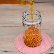 borcan cu bobițe de cătină peste care se toarnă miere de albine