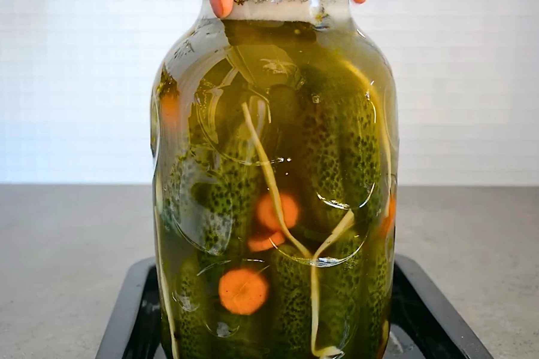 Borcan cu castraveți și saramură tulburată în timpul fermentației naturale