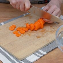 Morcovi feliați pentru murături, pregătiți pe tocător din lemn pentru rețeta de murături asortate de iarnă