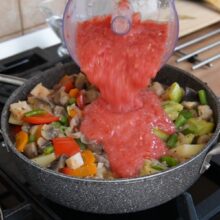 Roșii pasate adăugate în ghiveciul de legume pentru a crea un sos natural, fără apă suplimentară