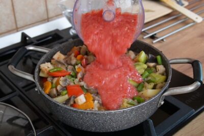 Roșii pasate adăugate în ghiveciul de legume pentru a crea un sos natural, fără apă suplimentară