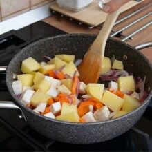 Cartofi, morcovi și țelină adăugați în oală, în ordinea corectă de gătire a legumelor în ghiveci