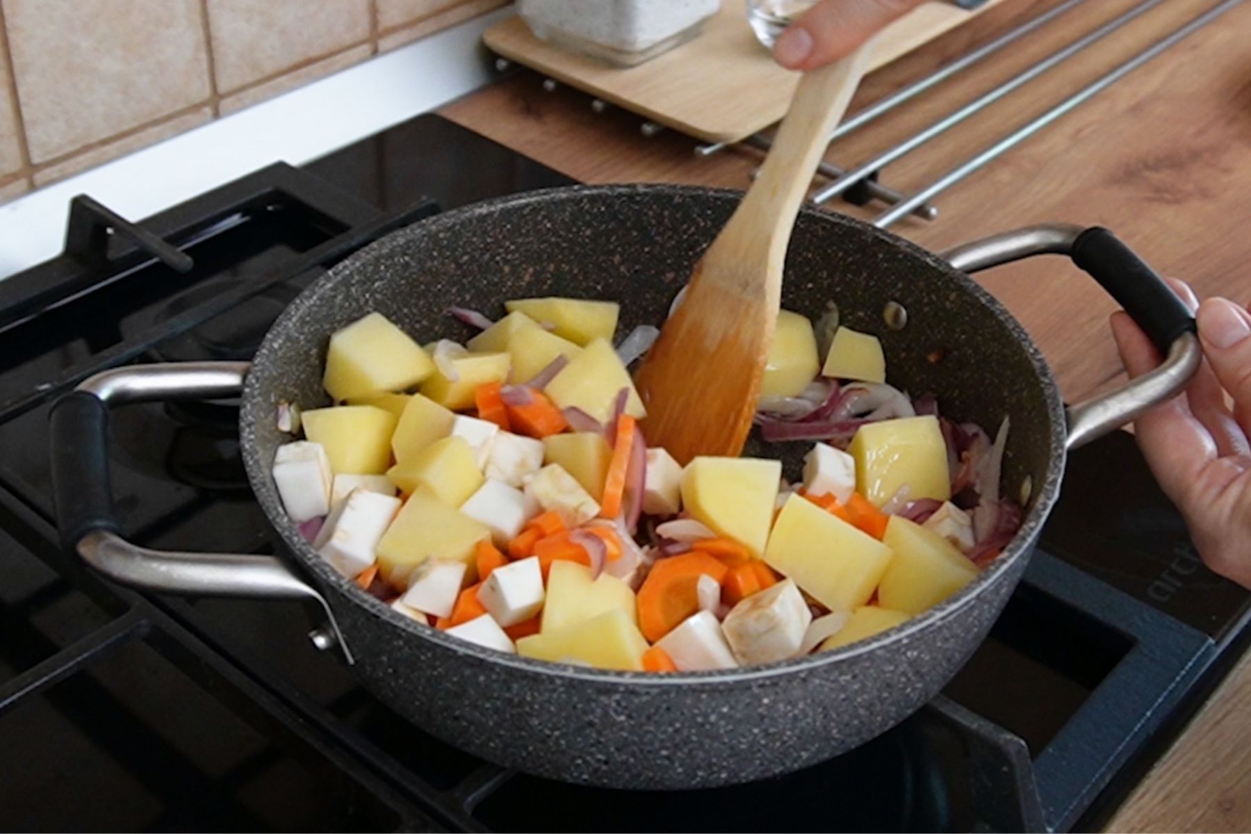 Cartofi, morcovi și țelină adăugați în oală, în ordinea corectă de gătire a legumelor în ghiveci