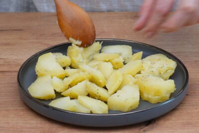 Cartofi fierți tăiați felii, pregătiți pentru salată cu iaurt și usturoi