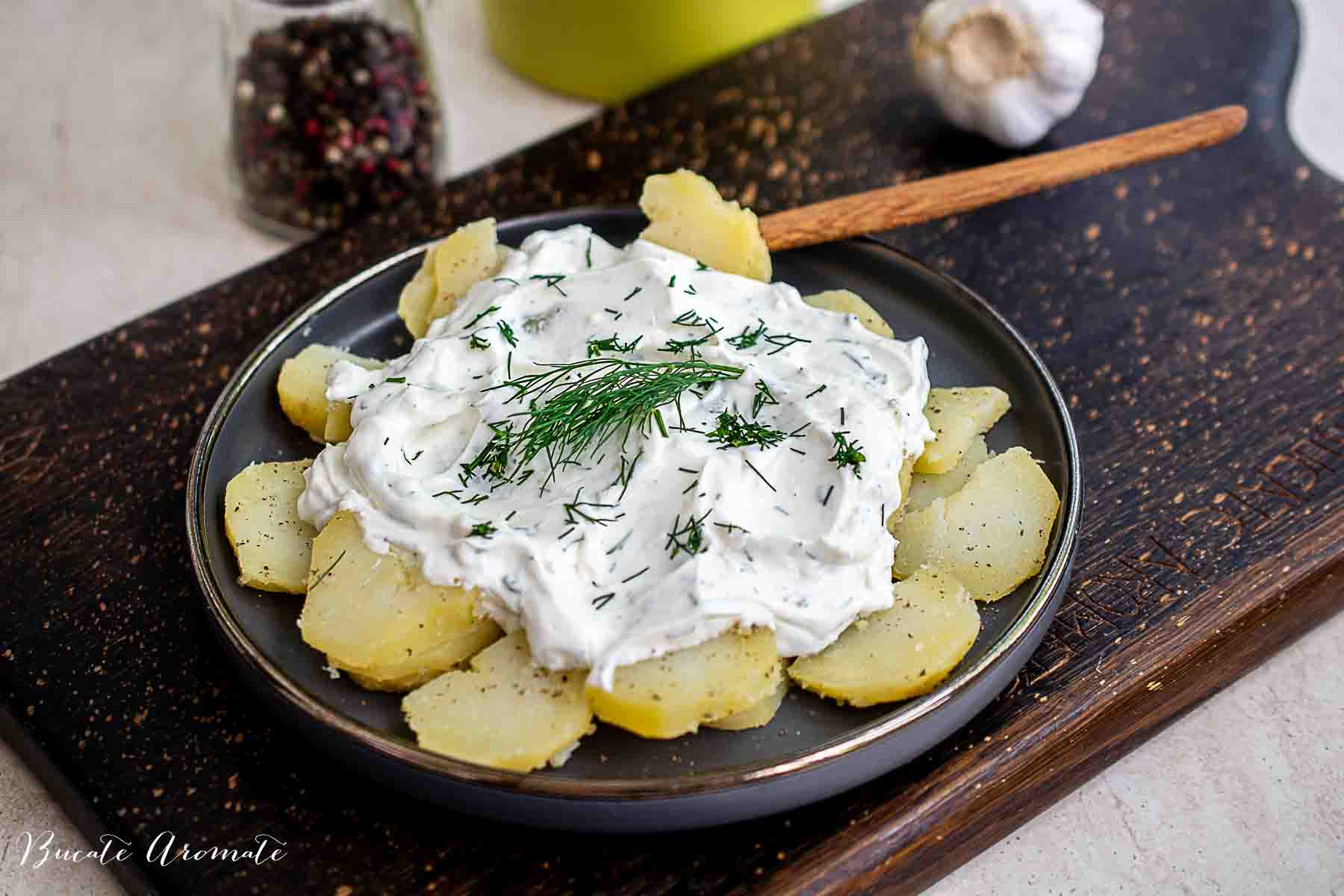 Salată de cartofi fierți cu sos de iaurt și mărar, servită pe farfurie rustică