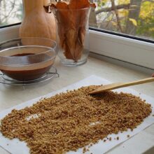 Nucile caramelizate pentru decorul ruladei sunt răspândite la răcit înainte de sfărâmare