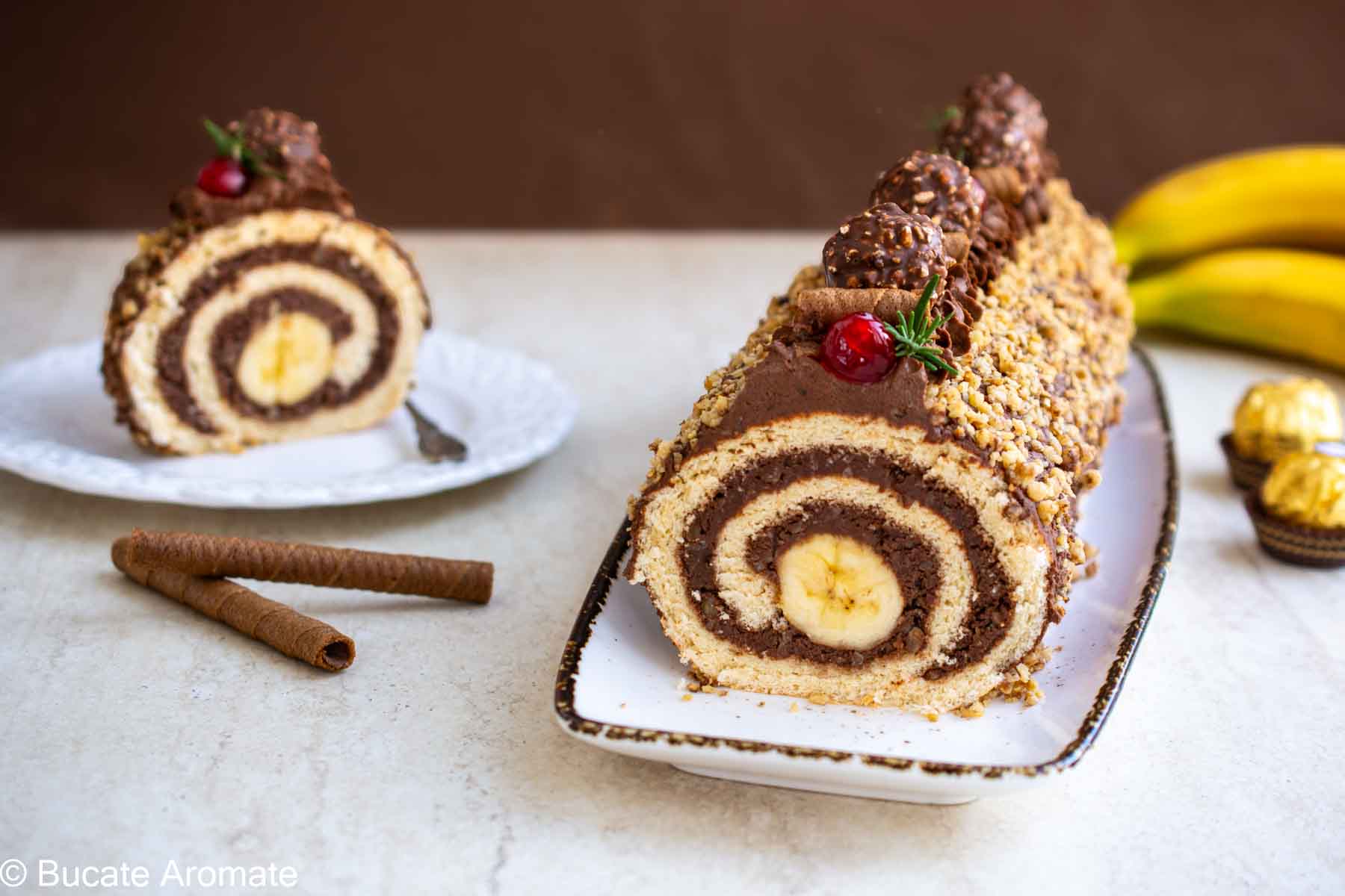 Ruladă cu cremă de ciocolată, banane și crocant de nuci, decorată festiv – ruladă întreagă și felie servită.
