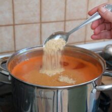 Presărarea condimentelor în supa cremă de ardei copți pentru ajustarea gustului