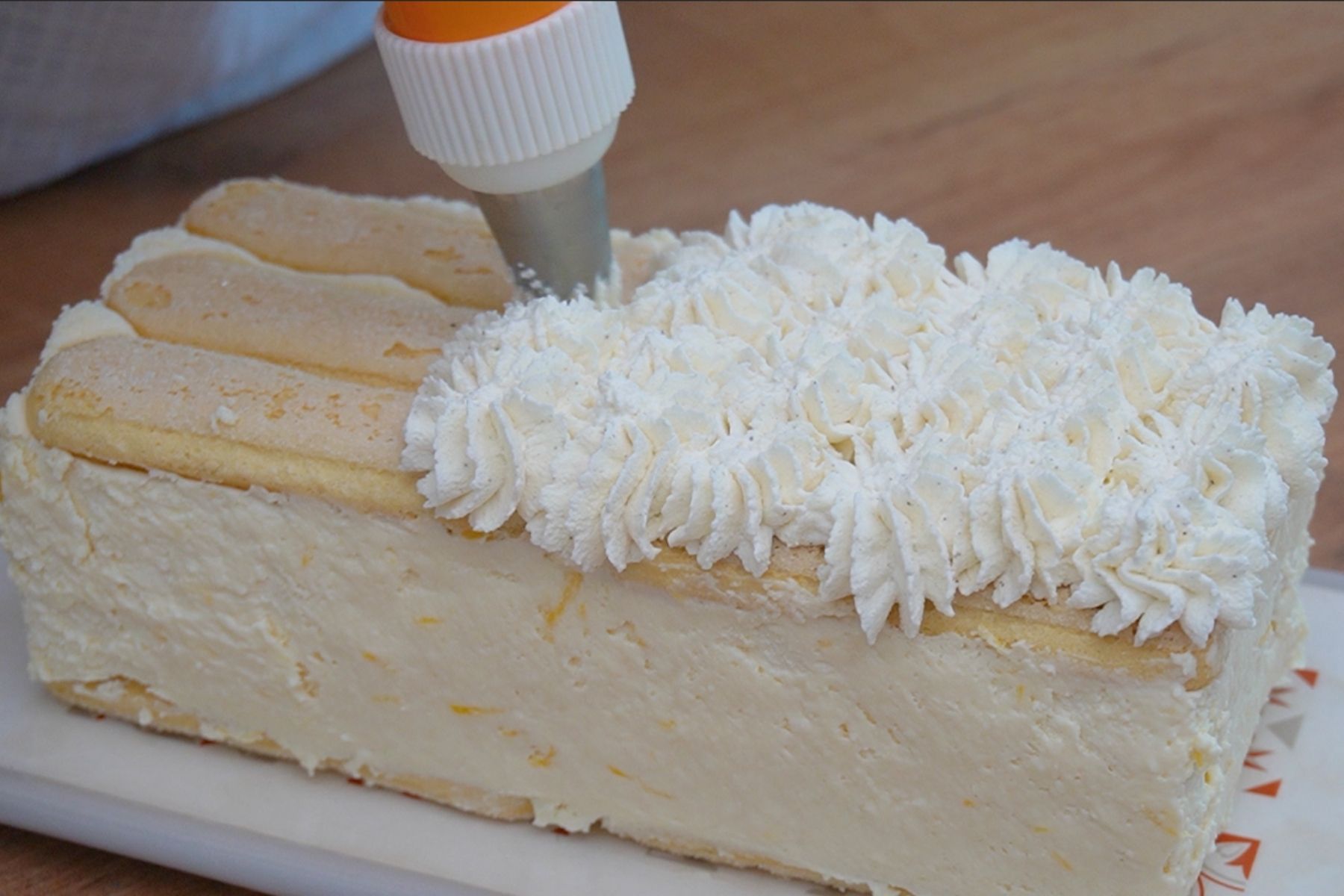 Decor cu frișcă naturală peste prăjitura cu pișcoturi și banane