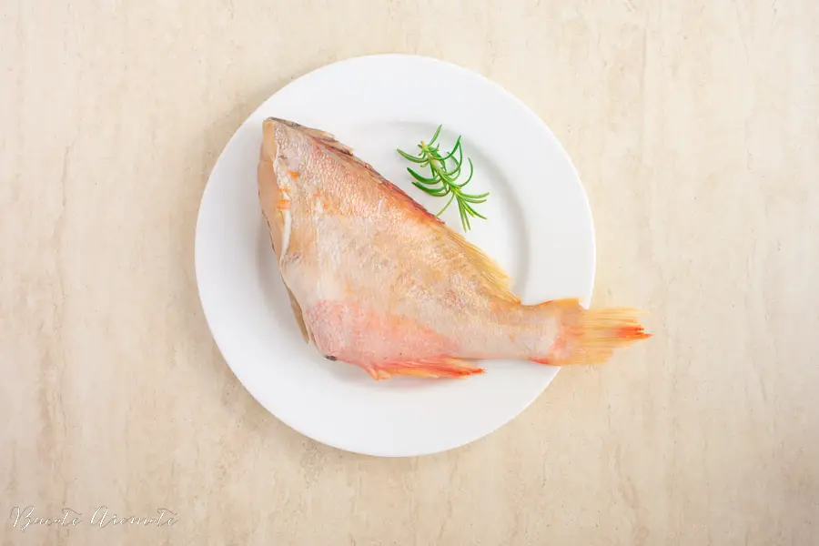 trunchi de red fish sau red snapper pe farfurie alba cu crenguta de rozmarin