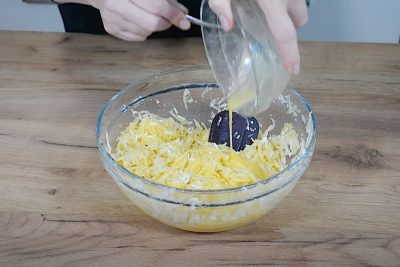 ouă bătute adăugate peste compoziția de budincă de cartofi rași în tavă