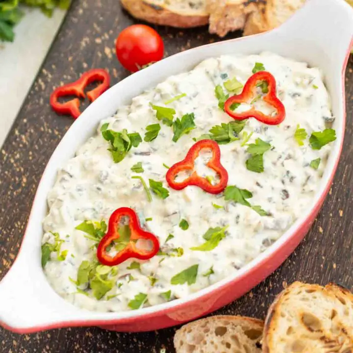 Castron cu salată ciuperci cu maioneză presărată cu pătrunjel.