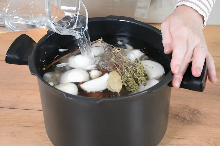 Fierbere boabe de fasole si ciolan in oala cu apa si condimente.