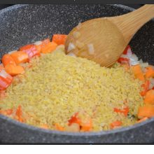 bulgur calit cu legume in cratita, amestecat cu lingura de lemn