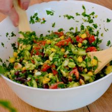 bol cu salata colorata amestecata cu doua linguri de lemn