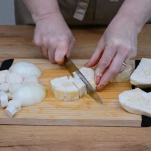 rădăcină de țelină tăiată cu cuțitul în cuburi pe un tocător de lemn