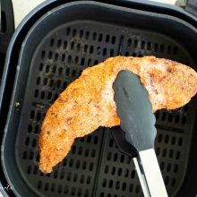 muschiulet de porc scos din airfryer cu un cleste de bucatarie