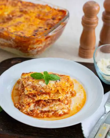 o felie de lasagna bolognese servita pe farfurie alba