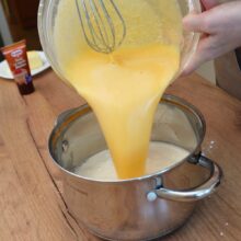amestec de galbenusuri pentru crema de vanilie turnat in oala cu lapte