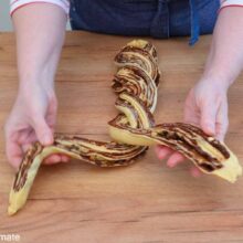 Ruloul de aluat tăiat pe lungime și împletit în două, cu umplutura de ciocolată vizibilă