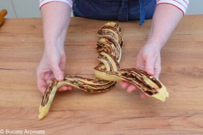 Ruloul de aluat tăiat pe lungime și împletit în două, cu umplutura de ciocolată vizibilă