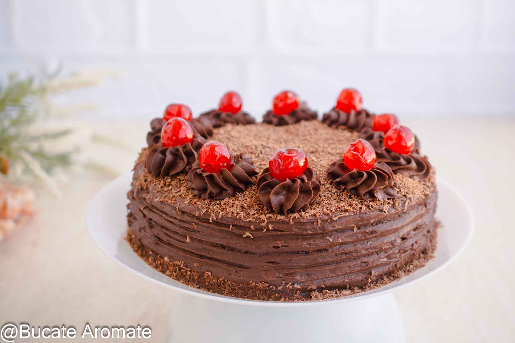 Tort de post cu ciocolată pe suport alb, decorat cu aveline de cremă, cireșe confiate și ciocolată rasă