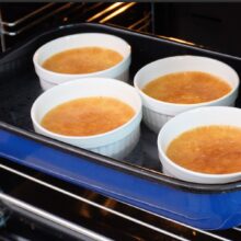 Crème brûlée coaptă în bain-marie, scoasă din cuptor, cu marginile ferme și centrul ușor tremurător.