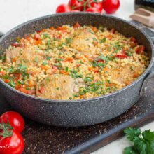 Cușcuș cu legume și carne de pui gătit complet, presărat cu pătrunjel verde și gata de servit.