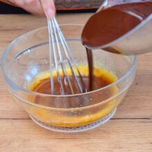 Ciocolată topită turnată peste ouă spumoase într-un bol de sticlă – compoziție pentru lava cake