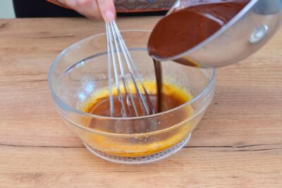 Ciocolată topită turnată peste ouă spumoase într-un bol de sticlă – compoziție pentru lava cake