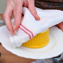Formă ramekin răsturnată pe farfurie cu ajutorul unui prosop – scoaterea lava cake-ului după coacere