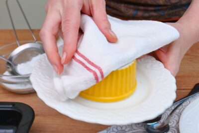 Formă ramekin răsturnată pe farfurie cu ajutorul unui prosop – scoaterea lava cake-ului după coacere