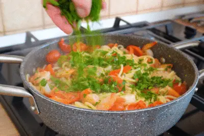 Finalizarea rețetei de spaghete cu creveți și roșii cu pătrunjel proaspăt tocat