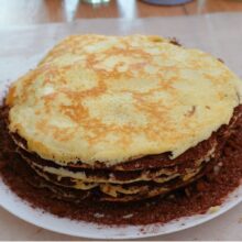 Ultima clătită așezată peste tortul unguresc de clătite cu cacao.