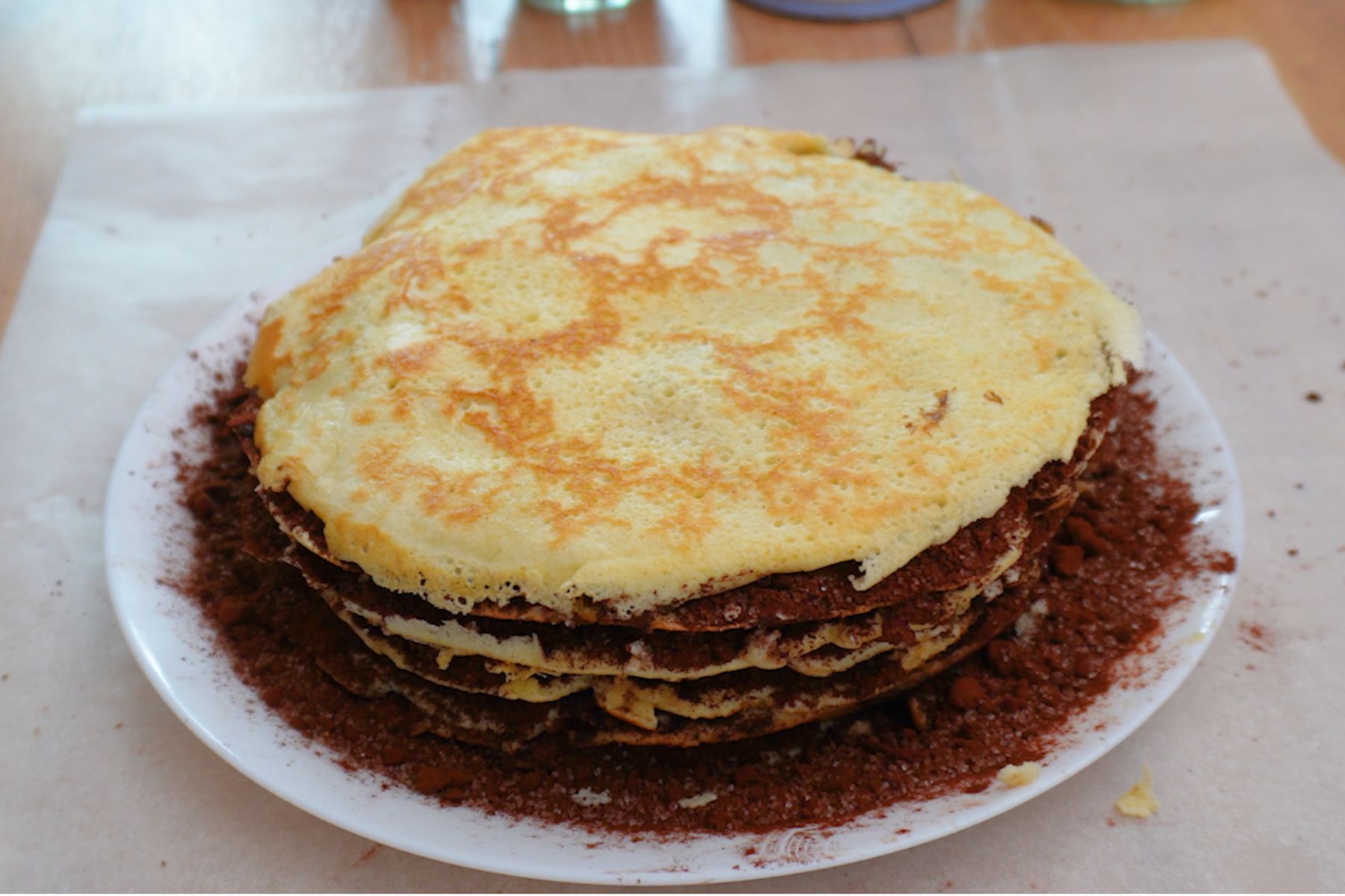 Ultima clătită așezată peste tortul unguresc de clătite cu cacao.